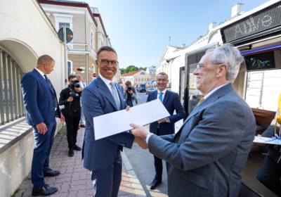 Alexander Stubb receiving a document from Väino Kaldoja in front of an Auve Tech shuttle